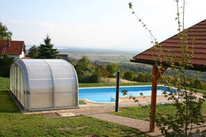 Une serre située à côté d’une piscine, avec vue sur la campagne.