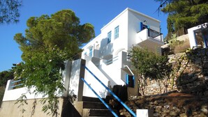 Ein weißes Geb äude mit blauen Akzenten, eine Steinmauer und eine Treppe, die davor führt.