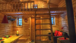 A log cabin interior with a wooden staircase, a dining area, and a cozy seating area. - Quaint holiday home in the forests of Lapland by the river (Sorsele)