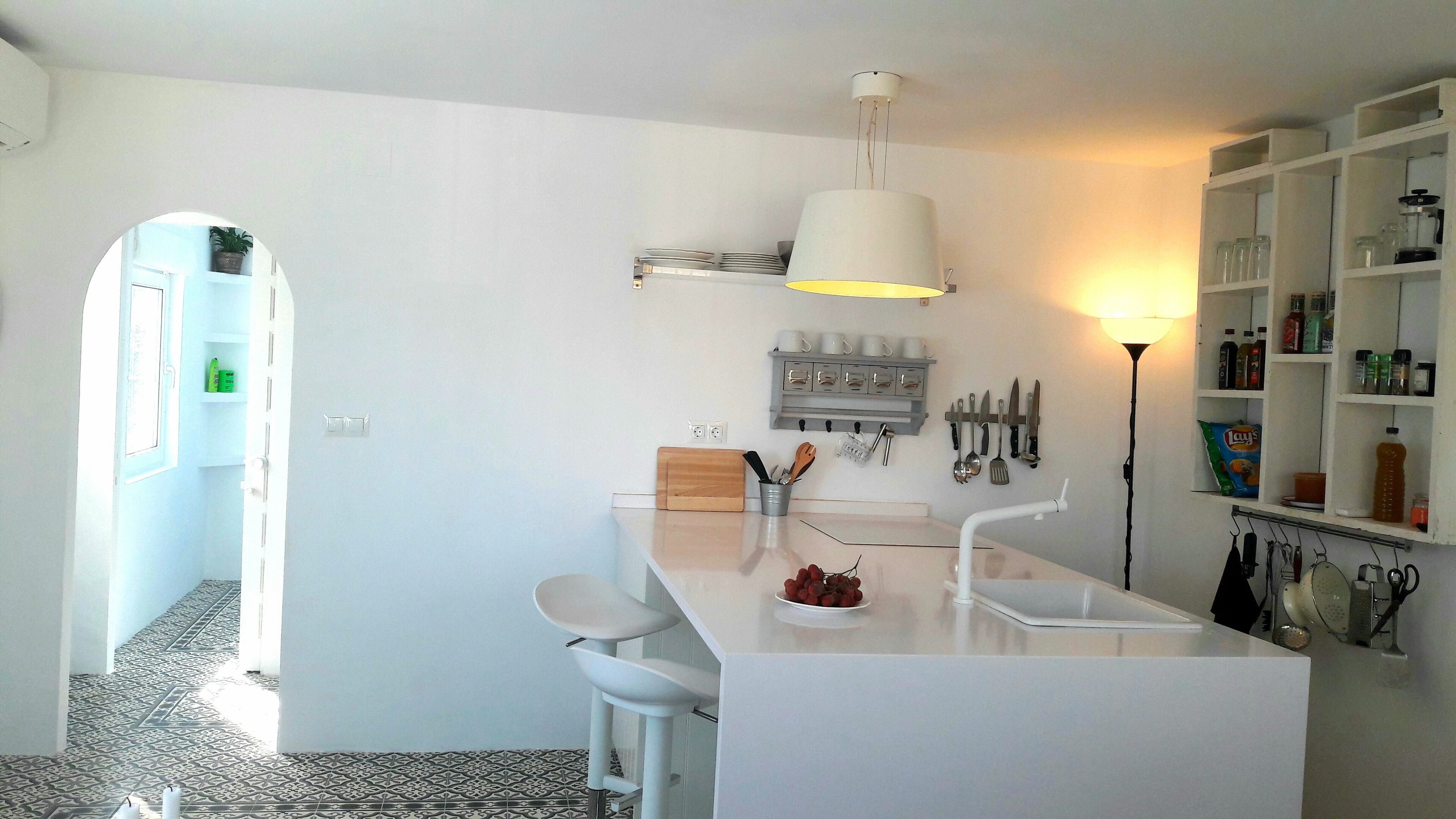 Une cuisine moderne dotée d’un îlot central, de meubles blancs et d’une variété d’ustensiles et d’appareils électroménagers.