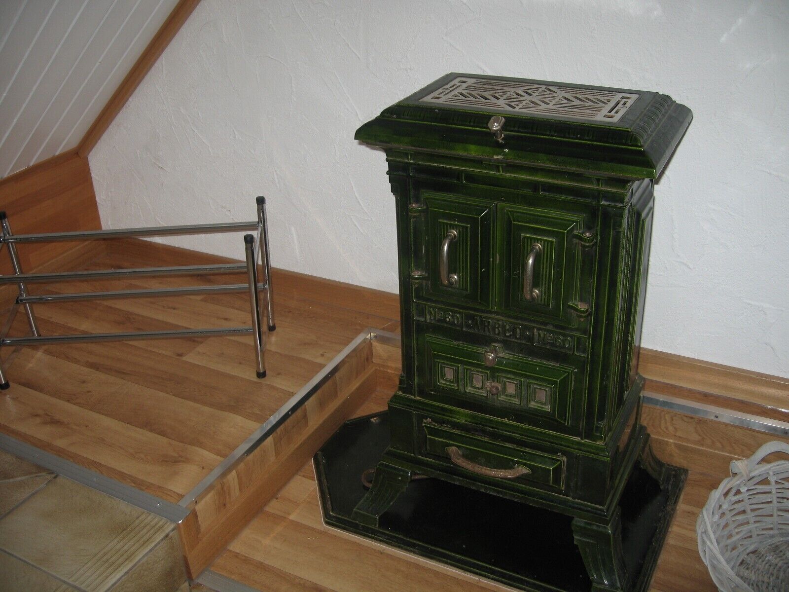 Una estufa verde antigua con un escurreplatos metálico sobre un suelo de madera.