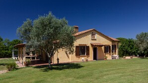 Une maison à deux étages, avec un toit en tuiles, une terrasse couverte et une pelouse bien entretenue.