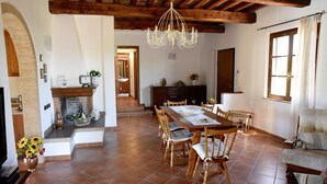Une salle à manger spacieuse avec une table et des chaises en bois, un lustre et une cheminée.