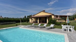 Une piscine avec des chaises longues et une table de patio.