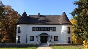 A large, white building with a symmetrical facade, a central entrance, and two conical roofs. - Villa Warzenburg, apartment 2 with panoramic view, balcony and fireplace. Vacation with a dog. (Friedrichroda)