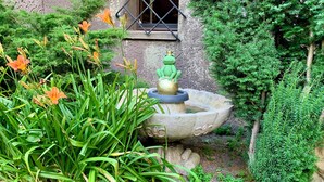 A garden with a stone fountain, a frog statue, and various plants. - Villa Warzenburg, apartment 2 with panoramic view, balcony and fireplace. Vacation with a dog. (Friedrichroda)