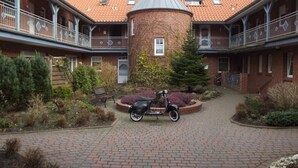 Ein Innenhof mit einem Backsteinhaus, einem zentralen Turm und einem abgestellten Roller.