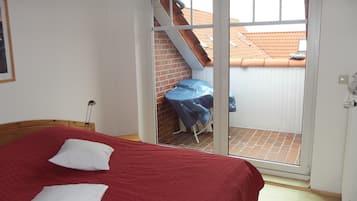A bedroom with a bed, a chair, and a sliding glass door leading to a balcony.