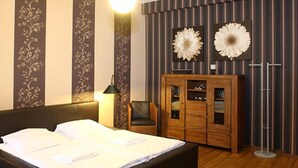 Ein Hotelzimmer mit einem großen Bett, einem Holzschrank und zwei daran befestigten Blumendekorationen.