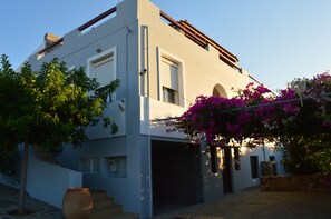 A modern two-story building with a garage, a staircase, and a large planter with flowering plants.