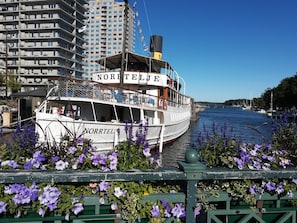A white boat named "NORRTEILE" docked at a pier with a cityscape in the background.
