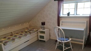 A bedroom with a bunk bed, a desk, a chair, and a window with curtains.