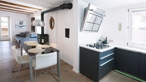 Una cocina moderna con encimera negra, sillas blancas y una mesa de comedor.