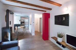 A modern living room with a fireplace, a dining area, and a kitchen in the background.
