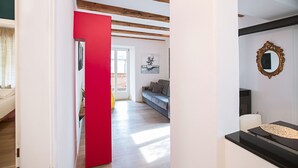 Un interior moderno con una pared roja de acento, techo de madera y un sofá al fondo.