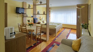 A compact room with a bed, a desk with a chair, a television mounted on the wall, and a coffee maker on the side table. - Holiday Apartment "Pharmacy" with Weinbergblick (Trittenheim)