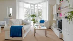 Una sala de estar moderna con un sofá blanco, una mesa de centro, un televisor y una estantería.