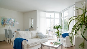 Una sala de estar moderna con un sofá blanco, una mesita de centro y un comedor con sillas y una mesa.