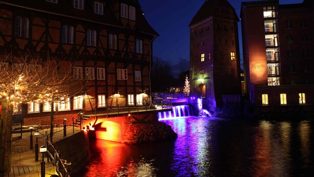 Un edificio histórico con una fuente de agua y ventanas iluminadas.