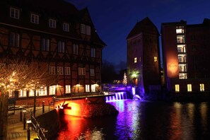 Un bâtiment historique doté d’un élément décoratif aquatique et de fenêtres illuminées.