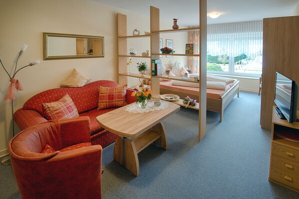 A cozy living room with a red sofa, a wooden coffee table, and a TV on a wooden stand. - Holiday Apartment "altars" with Weinbergblick (Trittenheim)