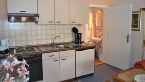 Een kleine keuken met een fornuis, spoelbak en keukenkastjes.