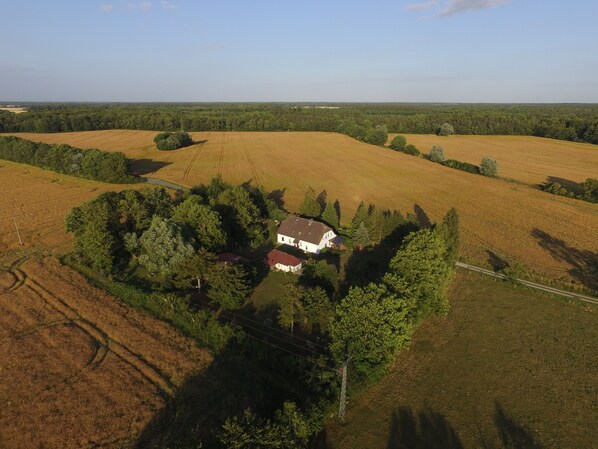 An aerial view of a rural property with a large white house surrounded by trees and fields.