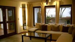 A living room with a sofa, a glass coffee table, and a view of the outside. - Complete apartment with garden use (Nußloch)