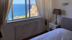 Une chambre avec vue sur la mer, un lit, une table de chevet avec une lampe et un radiateur.