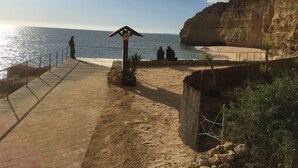 Une promenade en bord de mer dotée d’une structure en bois, d’une plage de sable et d’une falaise rocheuse.