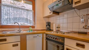 Une cuisine compacte équipée d’un lave-vaisselle Siemens, d’une cuisinière et d’une machine à café.