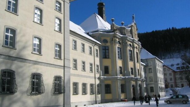 Un bâtiment historique doté de nombreuses fenêtres et dont le toit est recouvert de neige.