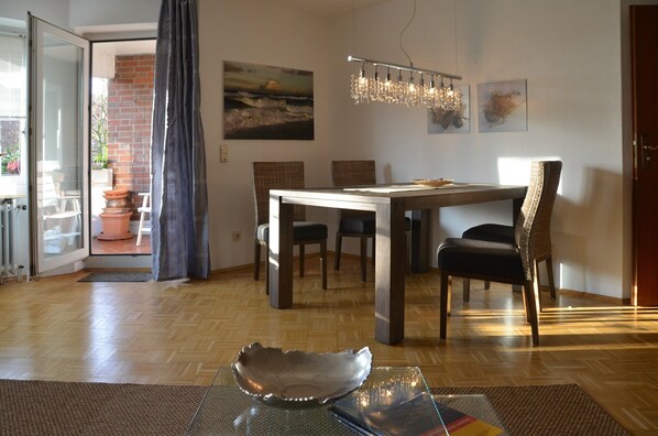 A dining area with a wooden table, chairs, and a modern chandelier.