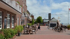 Un bâtiment en briques doté d’une terrasse, d’une tour horloge et d’une enseigne indiquant « Delfin Restaurant Café ».