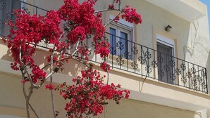 A two-story building with a balcony, potted plants, and a clear sky. - In the narrow streets of the old town, family-friendly, close to the beach (Ierapetra)