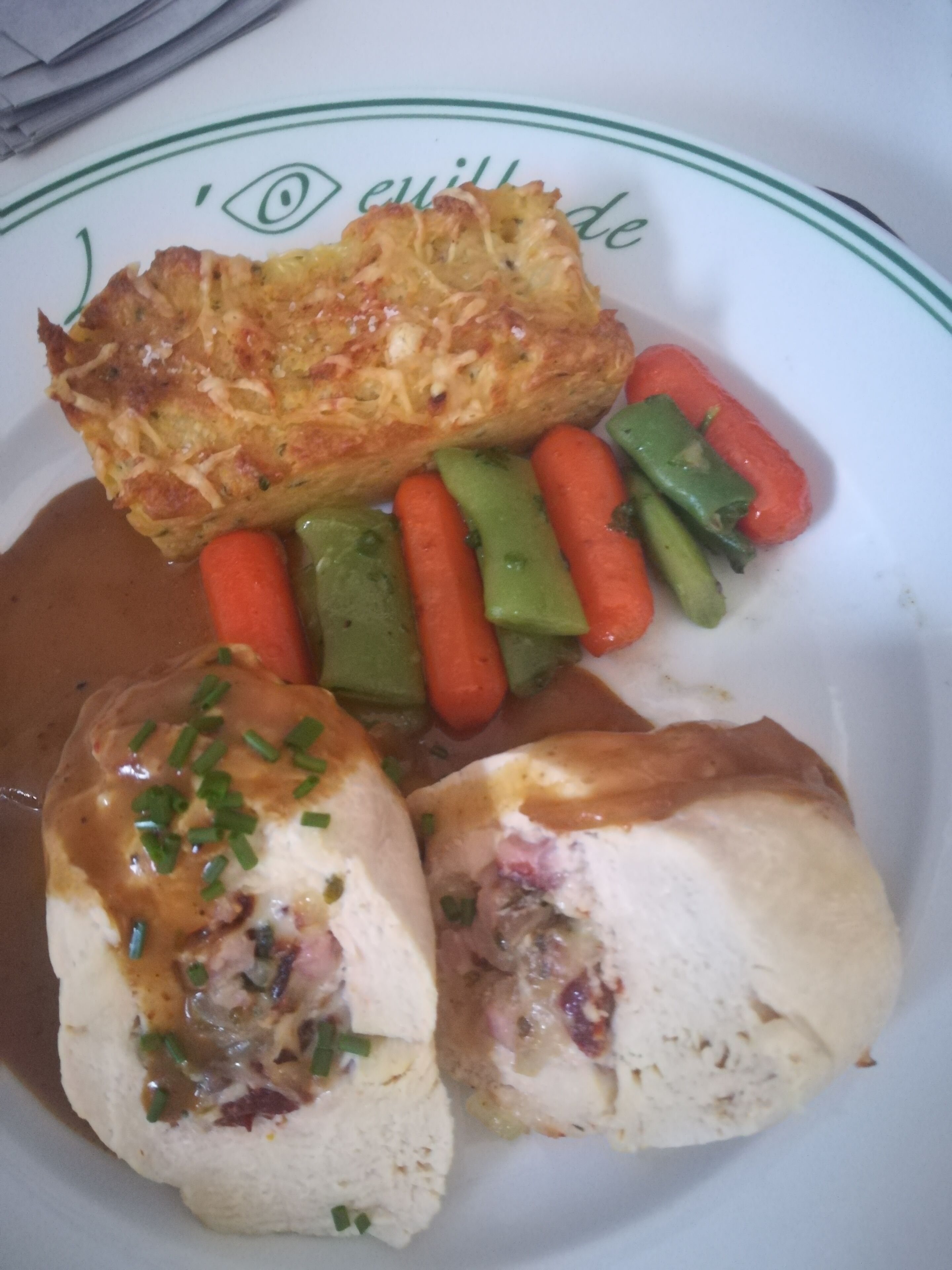 Une assiette contenant un morceau d’aliments frits, des légumes coupés en tranches et un plat de viande.