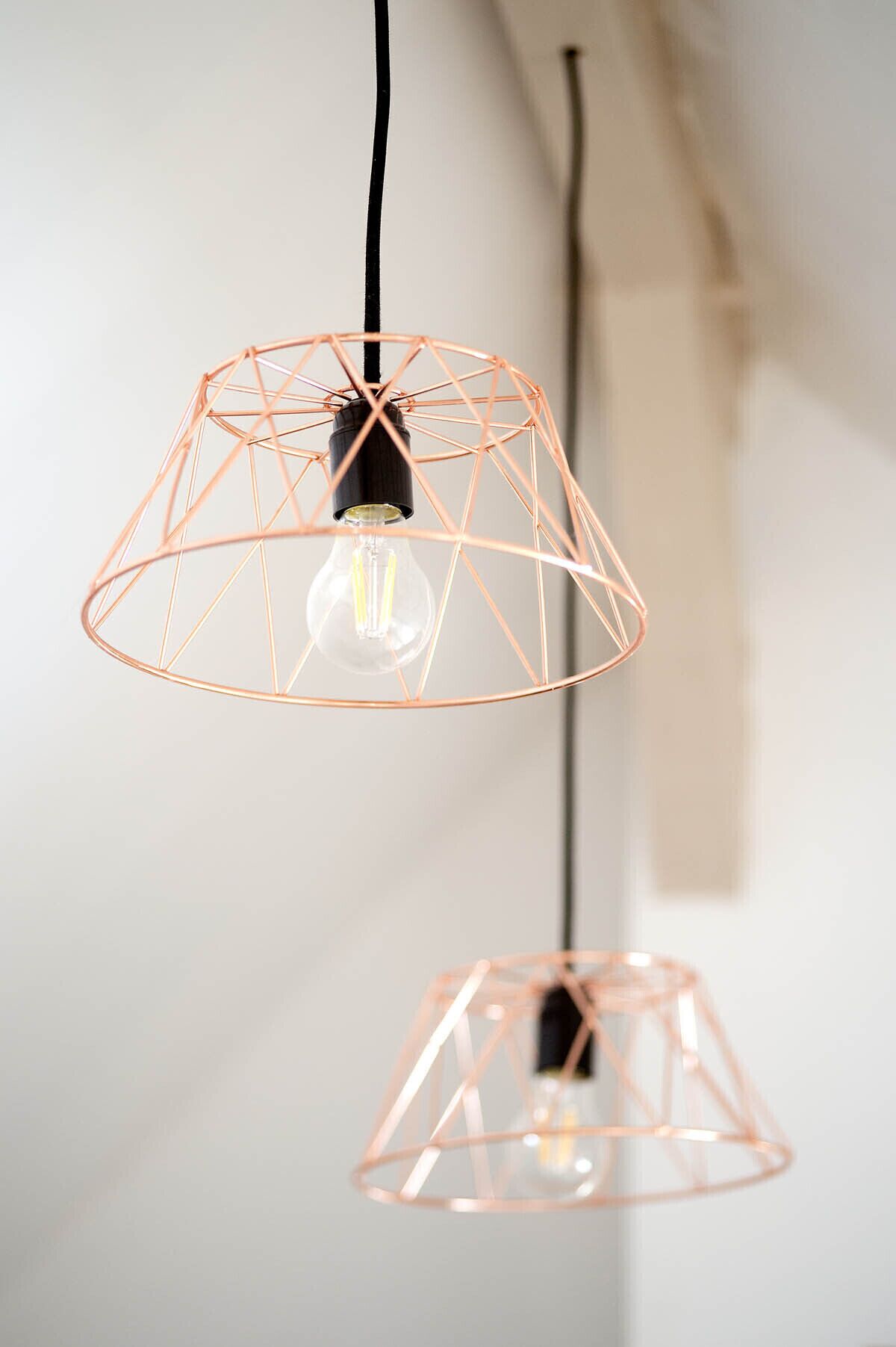 Zwei Pendelleuchten mit geometrischem Design und Glühbirne.
