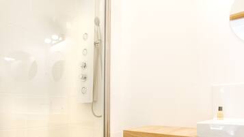 Ein modernes Badezimmer mit einer Glasdusche, einem Holzkästen und einem weißen Waschbecken.