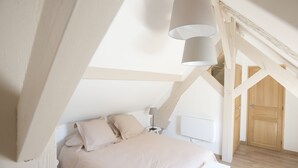 A bedroom with a bed, bedside table, lamp, and a wooden door. - L'OEUILLADE: calm and tranquility in Champagne (Œuilly)