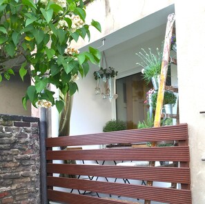 A wooden bench in an outdoor area with a brick wall and a hanging plant. - Charmant is centrally located, close to uni (Duisburg)