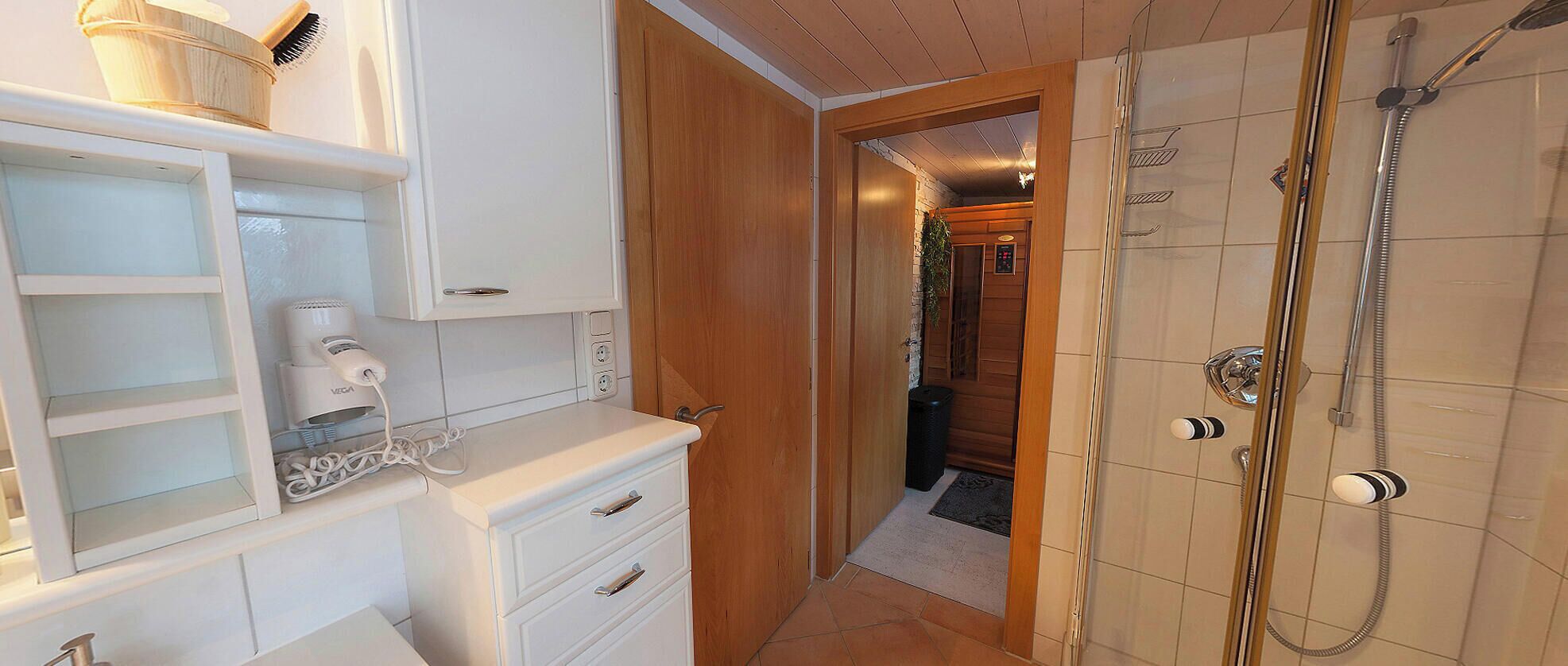 A modern bathroom with a shower, a vanity with a mirror, and a hairdryer.