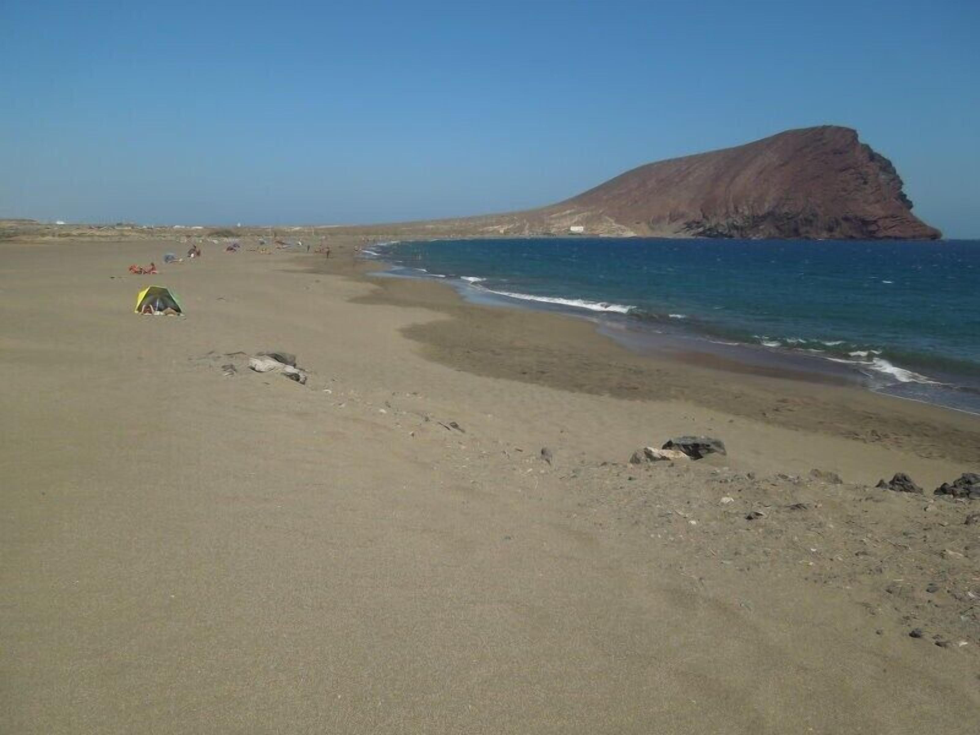 A beach with a tent and rocky terrain.