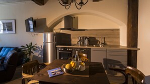 A modern kitchen with a wooden dining table, chairs, and a chandelier.