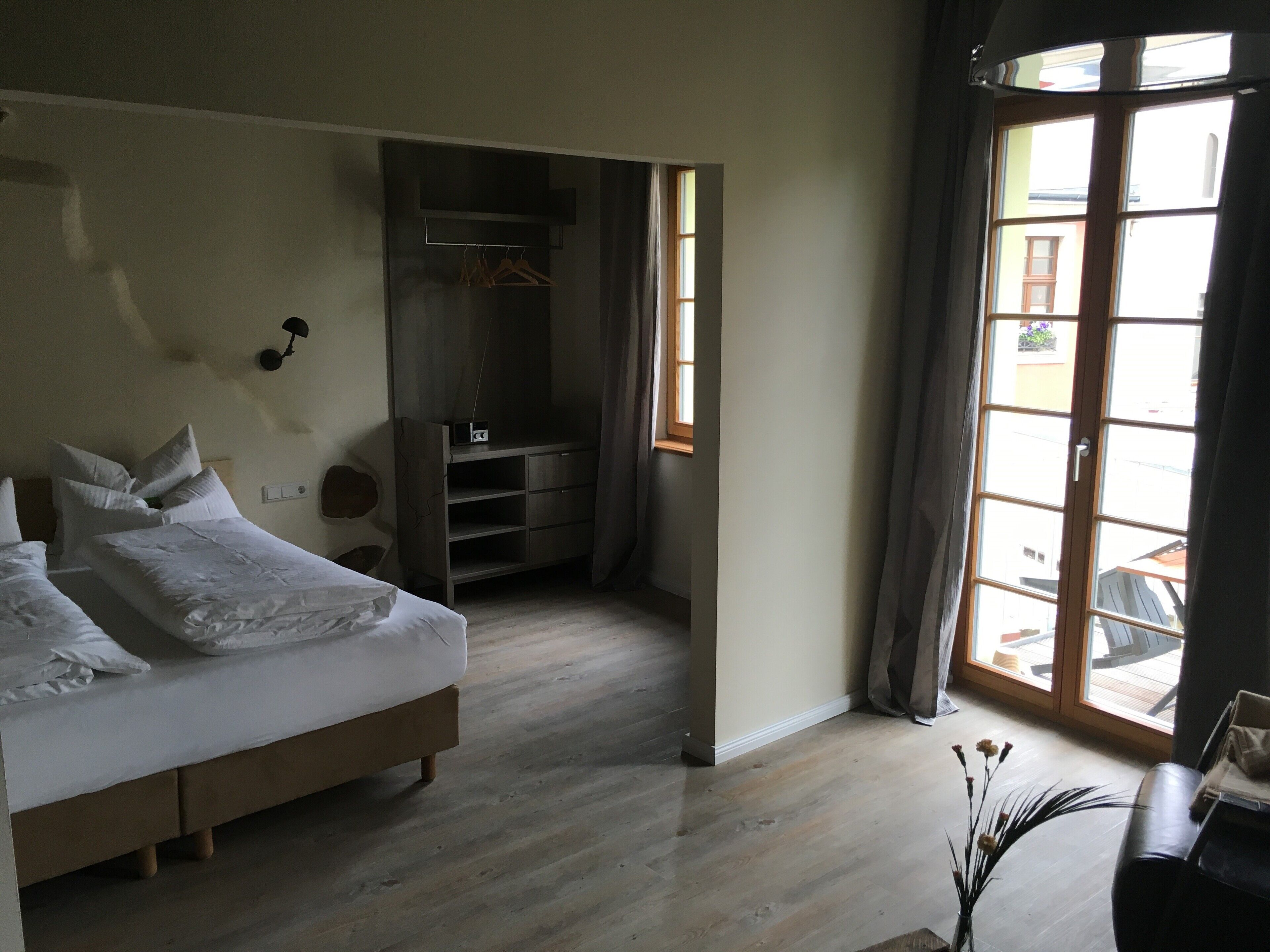 Ein Schlafzimmer mit einem Bett, einem Kleiderschrank und einem kleinen Schreibtisch mit Blumen in einer Vase.