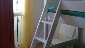Ein Etagenbett mit einer Leiter, eine grüne Decke, ein Poster an der Wand und ein Fenster mit Vorhängen.