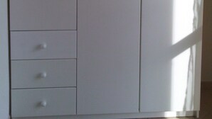 Ein großer weißer Kleiderschrank mit Schubladen und Türen.