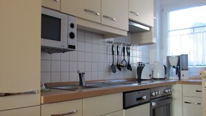 A kitchen with white cabinets, a microwave, a stove, and a dishwasher. - Comfortable holiday home **** (incl. W-Lan) in the best location of Carolinensiel (Carolinensiel)