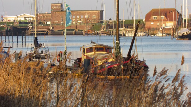 A marina with several boats docked, a bridge in the background, and buildings along the waterfront. - Comfortable holiday home **** (incl. W-Lan) in the best location of Carolinensiel (Carolinensiel)