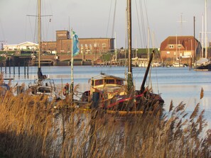 Un port de plaisance où sont amarrés plusieurs bateaux, un pont en arrière-plan et des bâtiments le long de la rive.