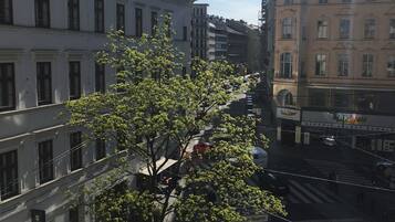A street view with a tree-lined sidewalk, buildings with classical architecture, and a clear sky.